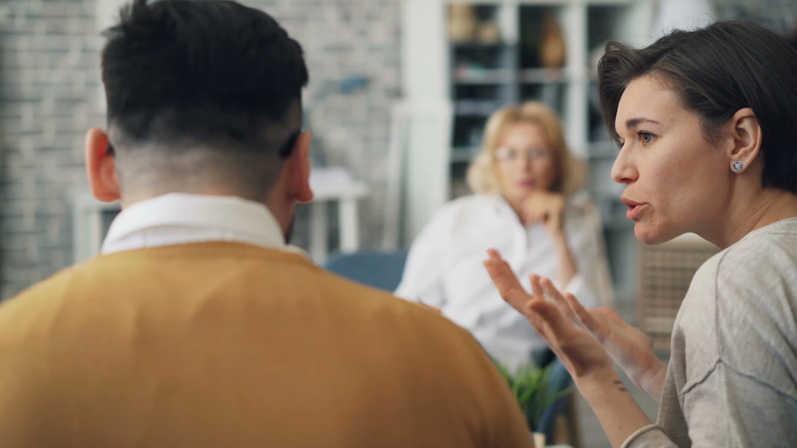 Two people seated at a table having a calm but focused conversation, representing a family member walking a respite provider through the situation at home