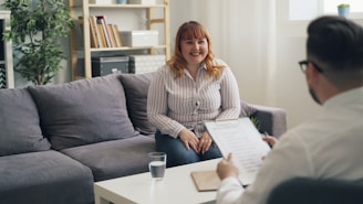 a woman sitting on a couch talking to a man