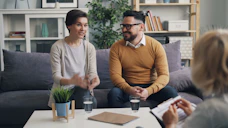a man and woman sitting on a couch talking to each other