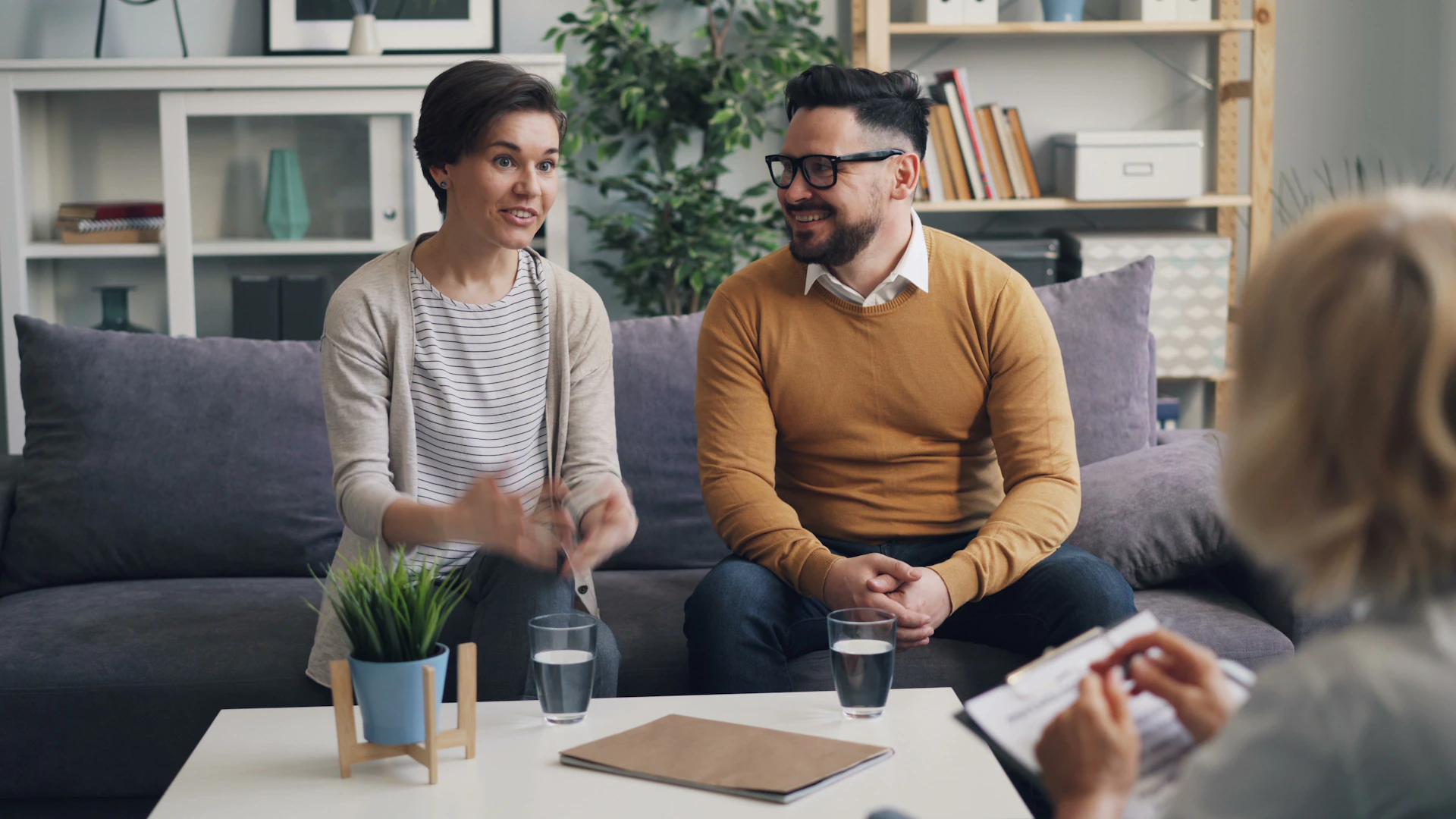 a man and woman sitting on a couch talking to each other