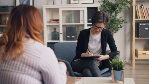a woman sitting on a couch with a clipboard in her hand