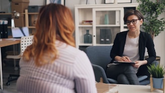 a woman sitting in a chair talking to another woman
