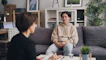 a woman sitting on a couch talking to another woman