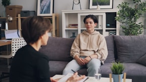 a woman sitting on a couch talking to another woman