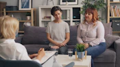two women sitting on a couch talking to each other