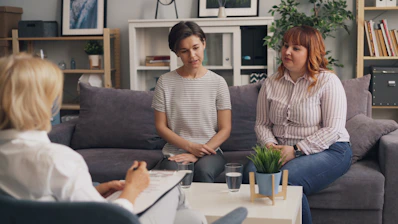 two women sitting on a couch talking to each other