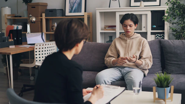 a woman sitting on a couch talking to another woman