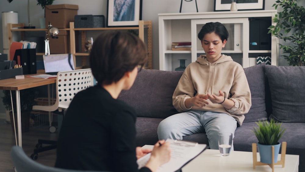 a woman sitting on a couch talking to another woman