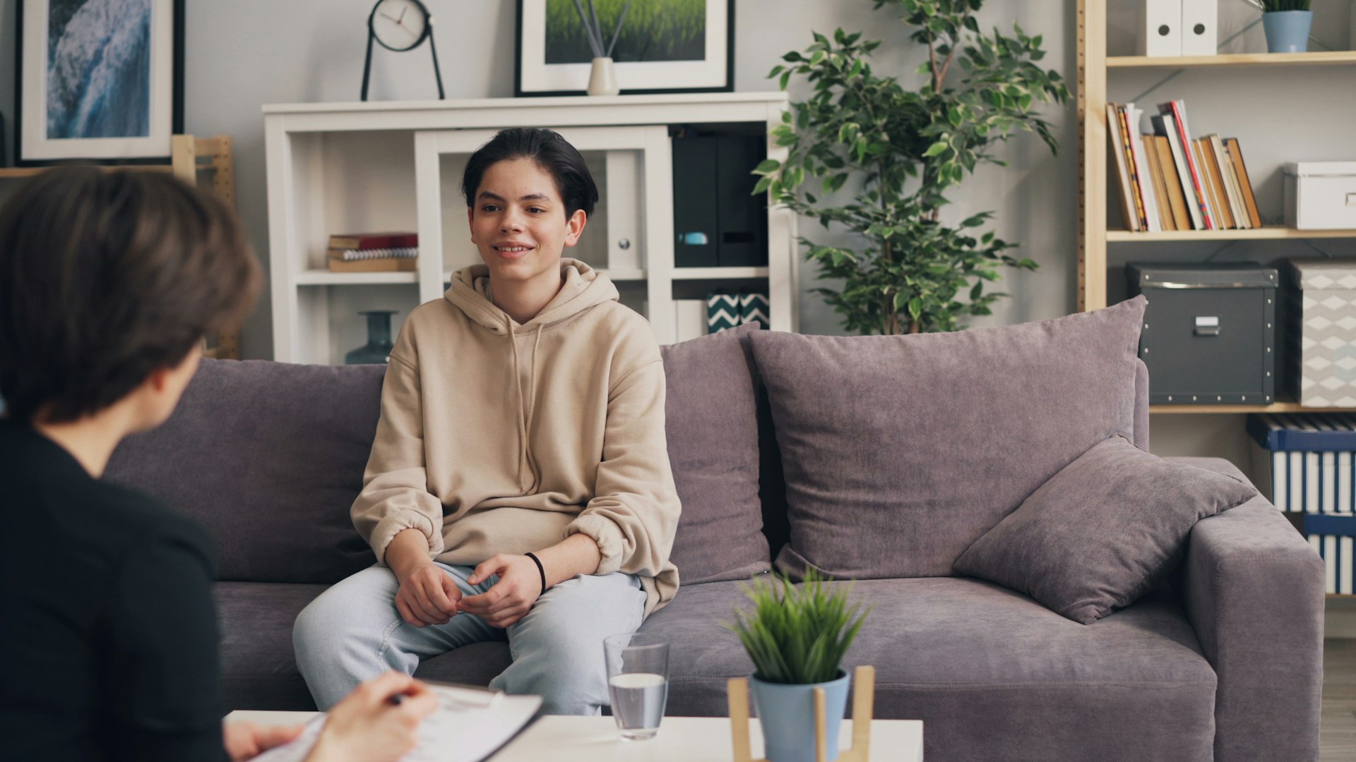 A woman sitting on a couch talking to a therapist in a warm, comfortable counseling space