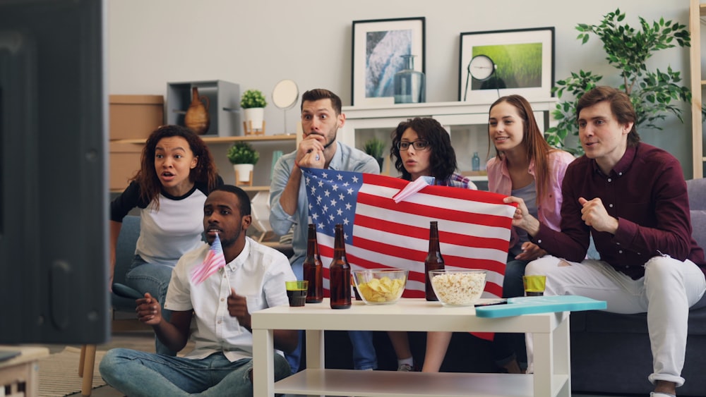 a group of people sitting on a couch holding an american flag