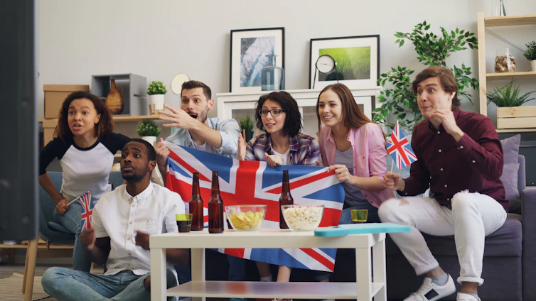 a group of people sitting on a couch holding a british flag