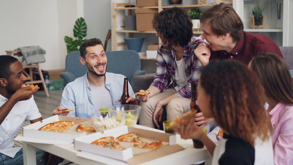 a group of people sitting around a table eating pizza