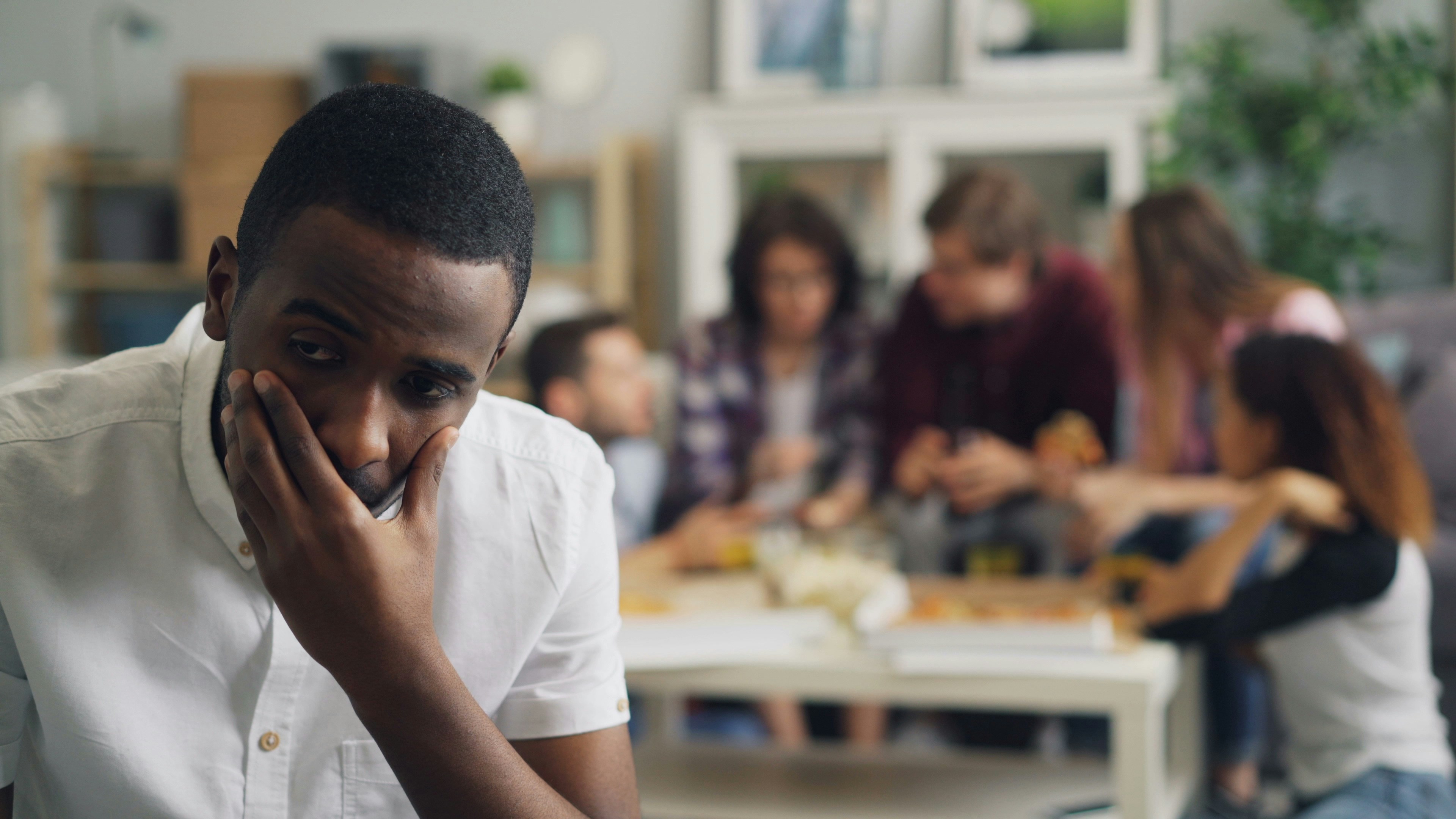 a man holding his hand to his face in front of a group of people