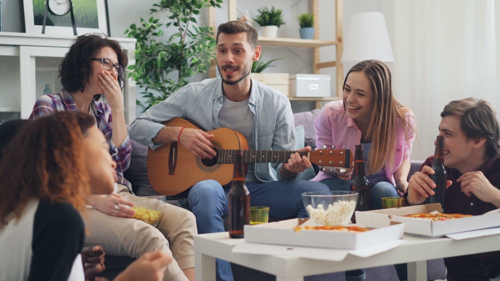 a group of people sitting around a table with a guitar