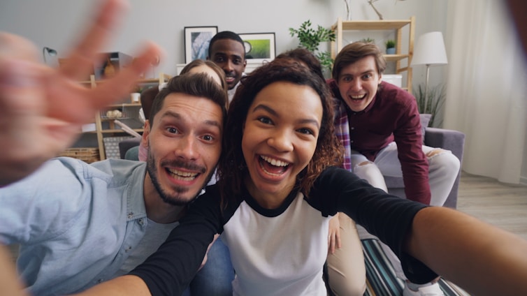 a group of friends taking a selfie in a living room