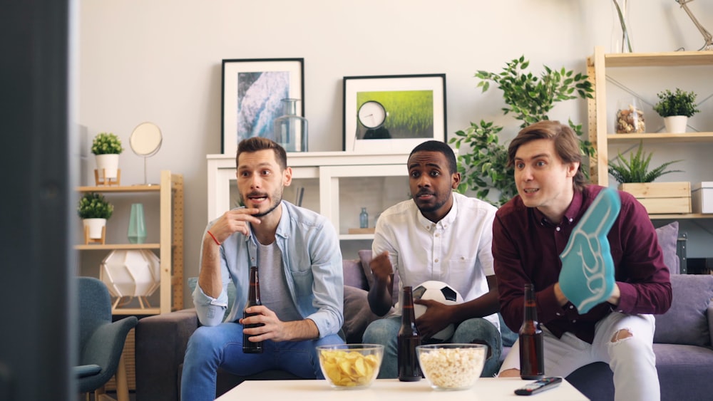 three men sitting on a couch in a living room