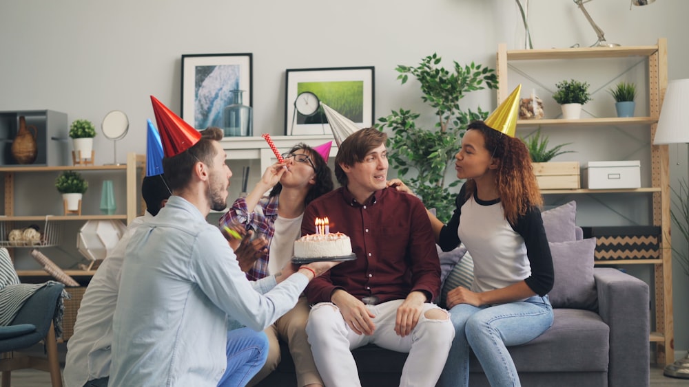 a group of people sitting on a couch with a cake