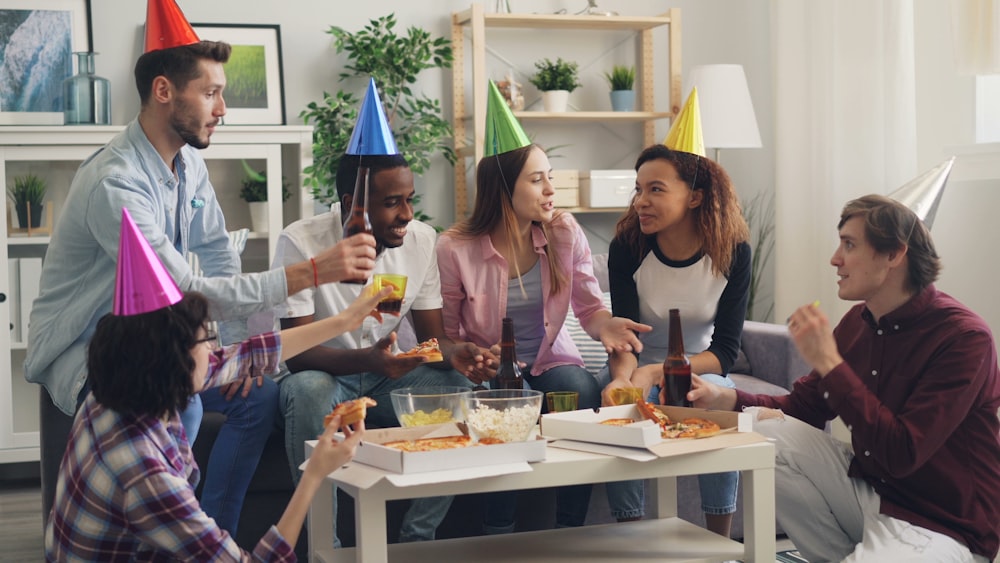 a group of people sitting around a table wearing party hats