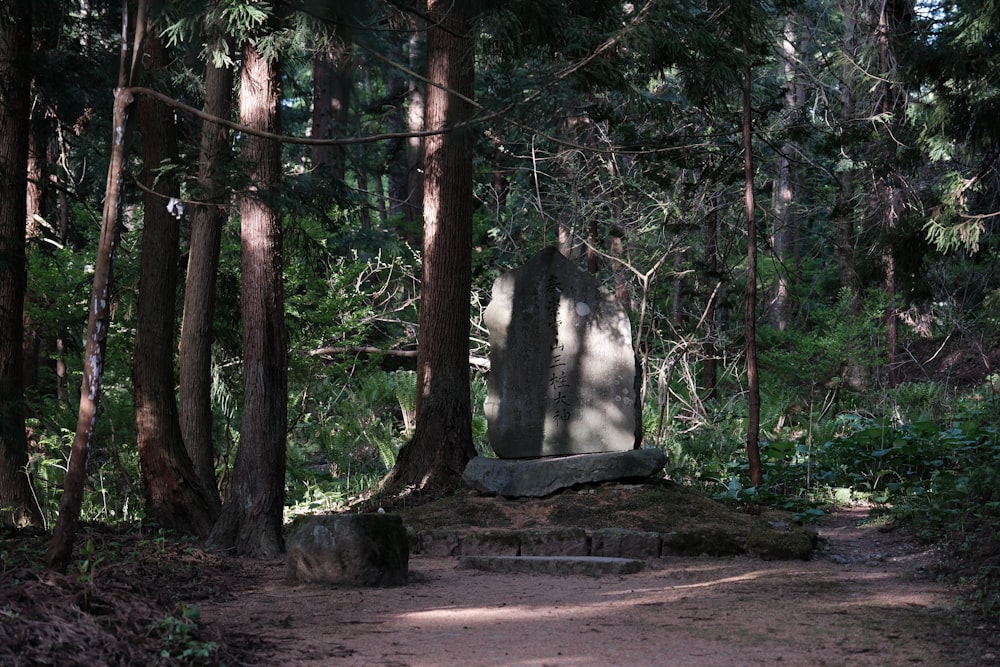 a path through a forest with a stone monument in the middle