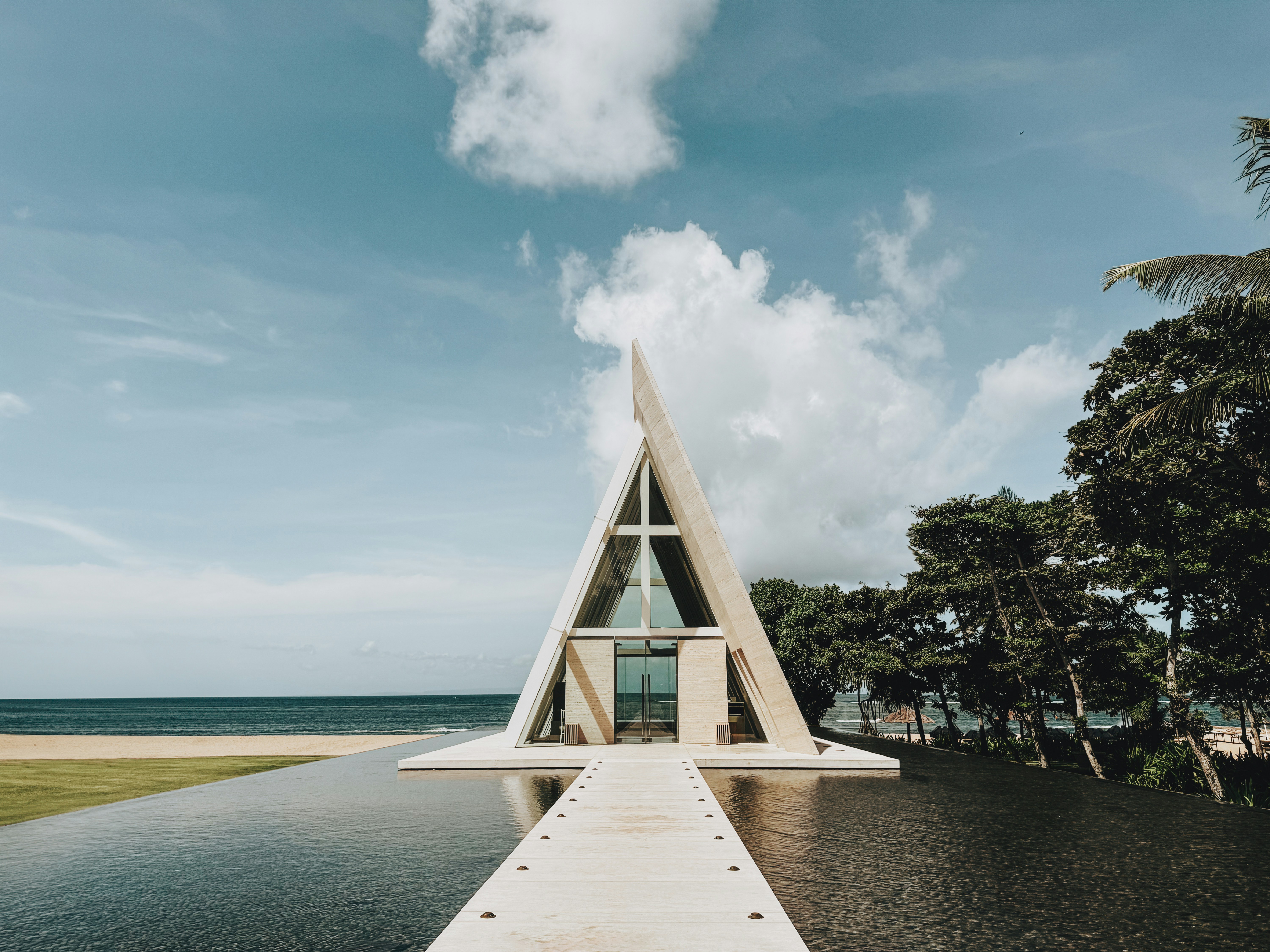 a triangular building sitting on top of a body of water, 