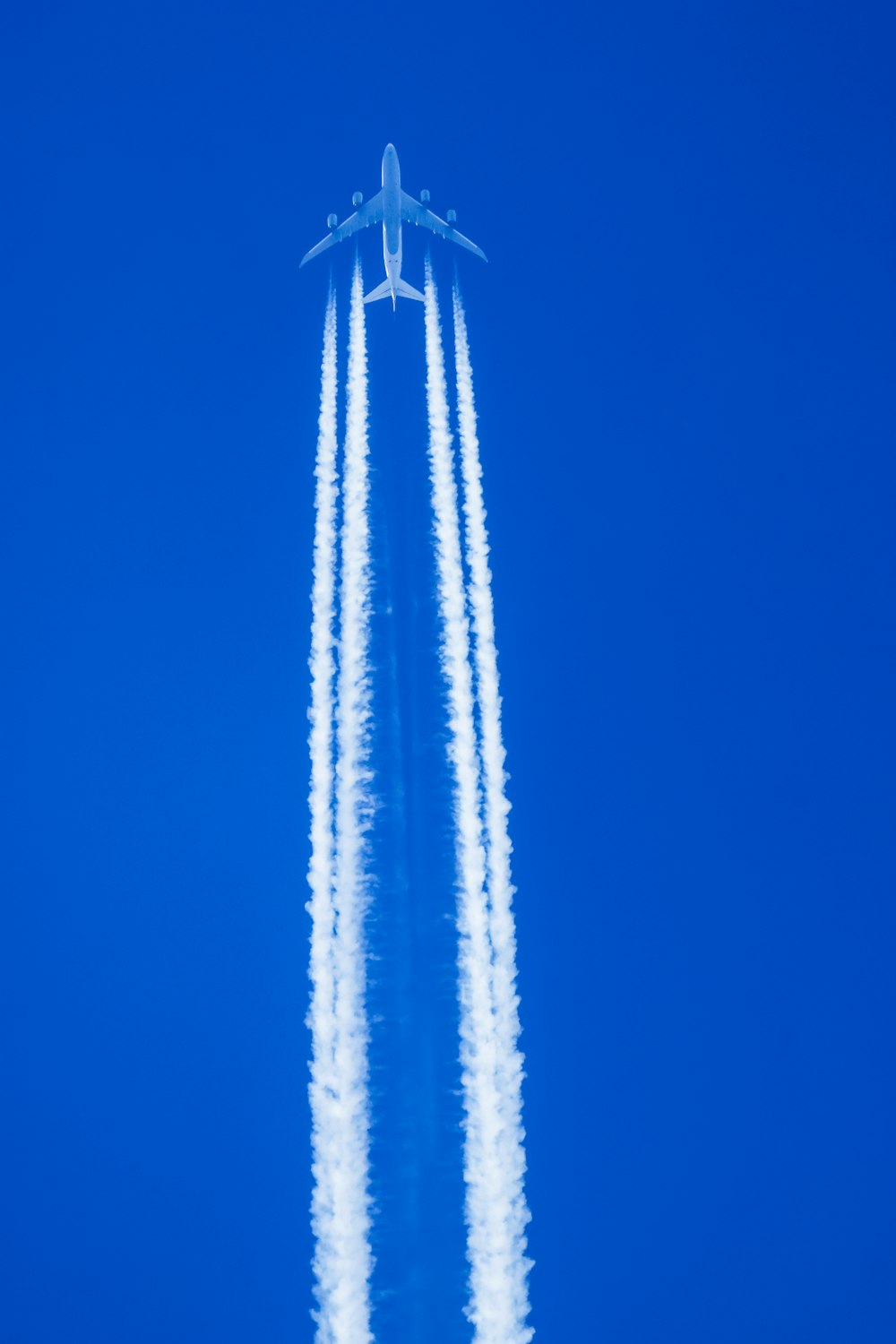 a jet flying through a blue sky leaving a trail of smoke behind it
