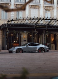 a silver sports car parked in front of a hotel