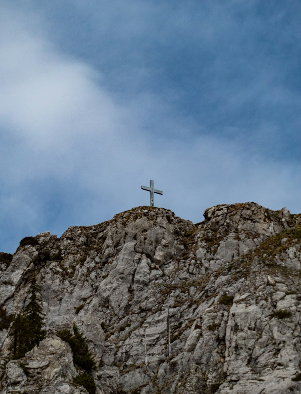 a cross on top of a mountain with a sky background