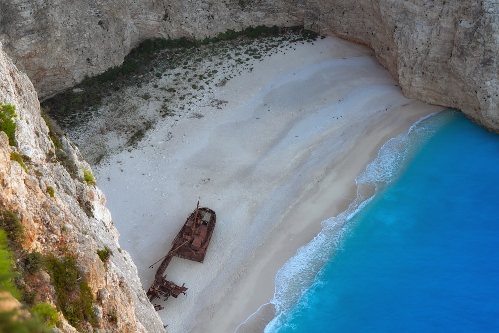 a boat sitting on top of a sandy beach next to the ocean