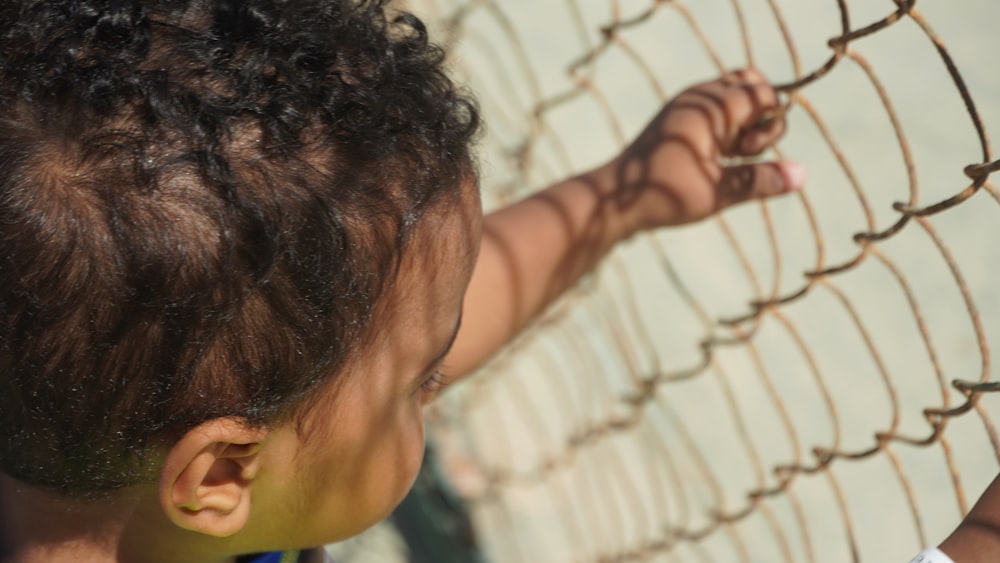 a young child is reaching into a fence