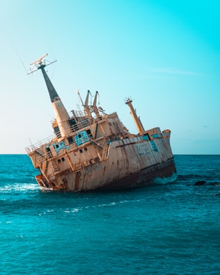 an old rusted ship in the middle of the ocean