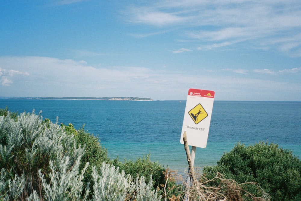 a warning sign on a beach near the ocean