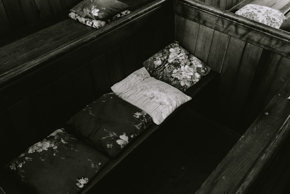 a black and white photo of a bench with pillows