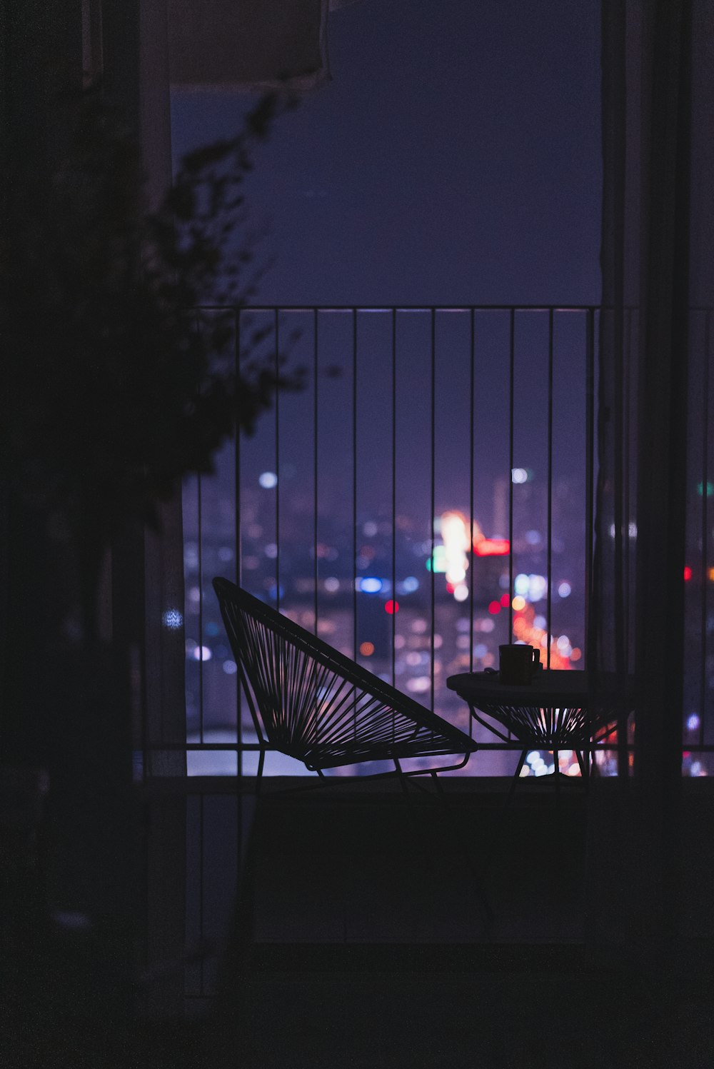 a chair and table on a balcony overlooking a city at night