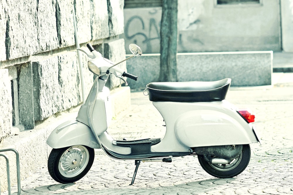 a white scooter parked on a cobblestone street