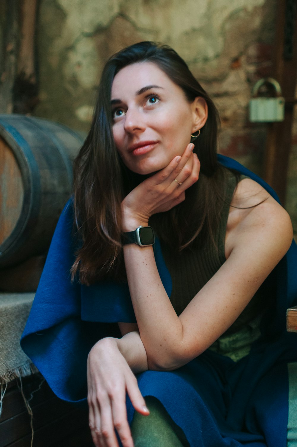 a woman sitting on a bench next to a barrel