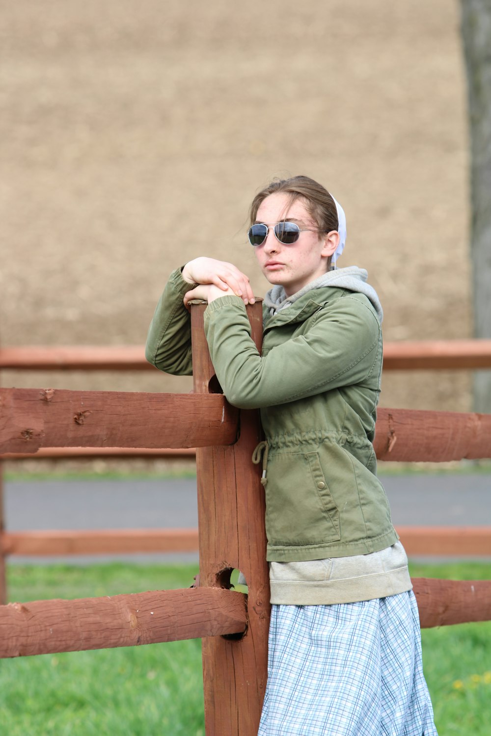 a woman leaning on a fence with her arms crossed