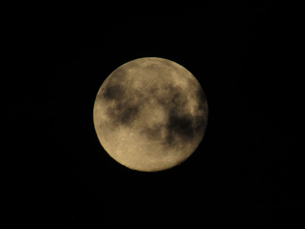 a full moon is seen in the dark sky