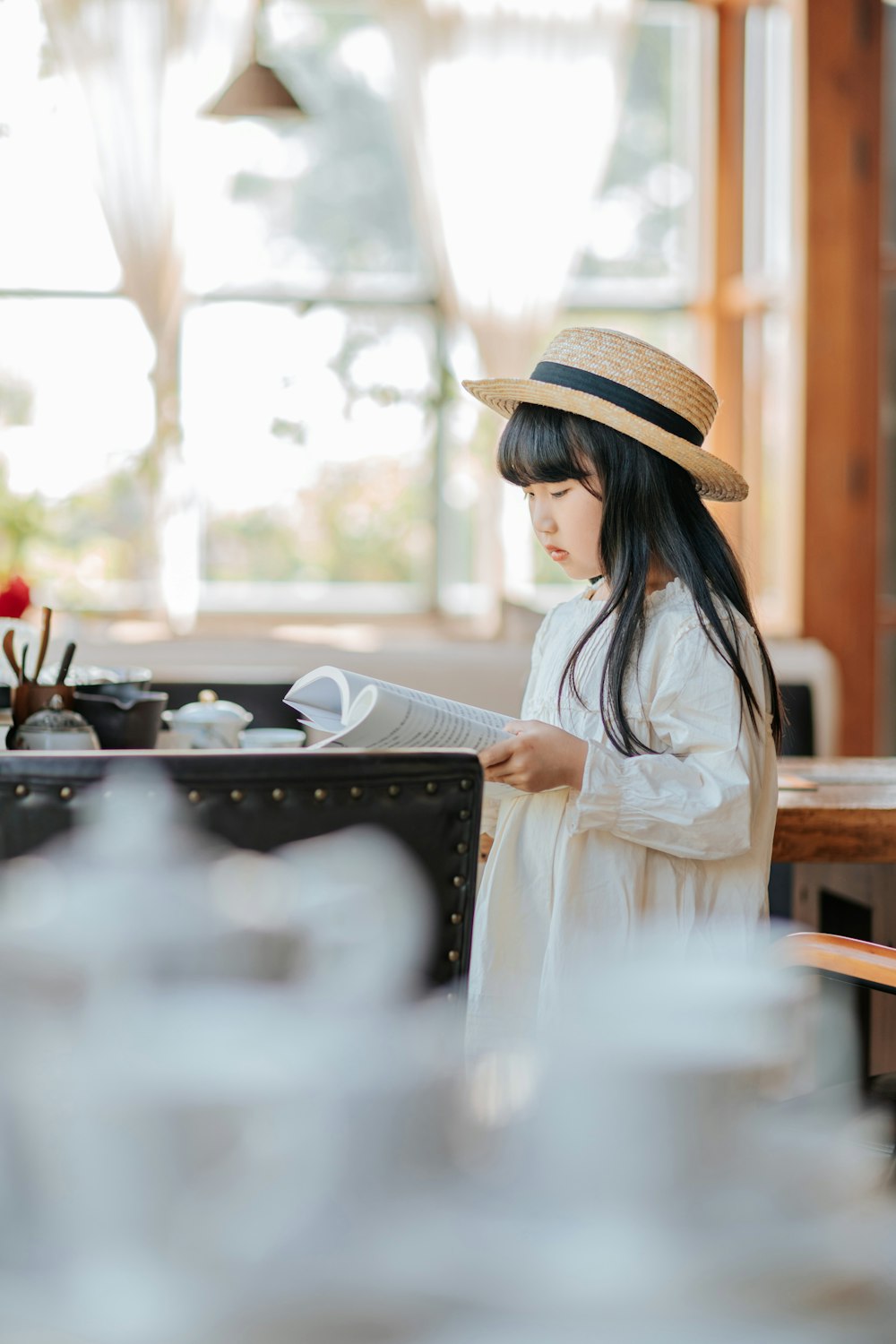 a young girl wearing a hat and reading a book