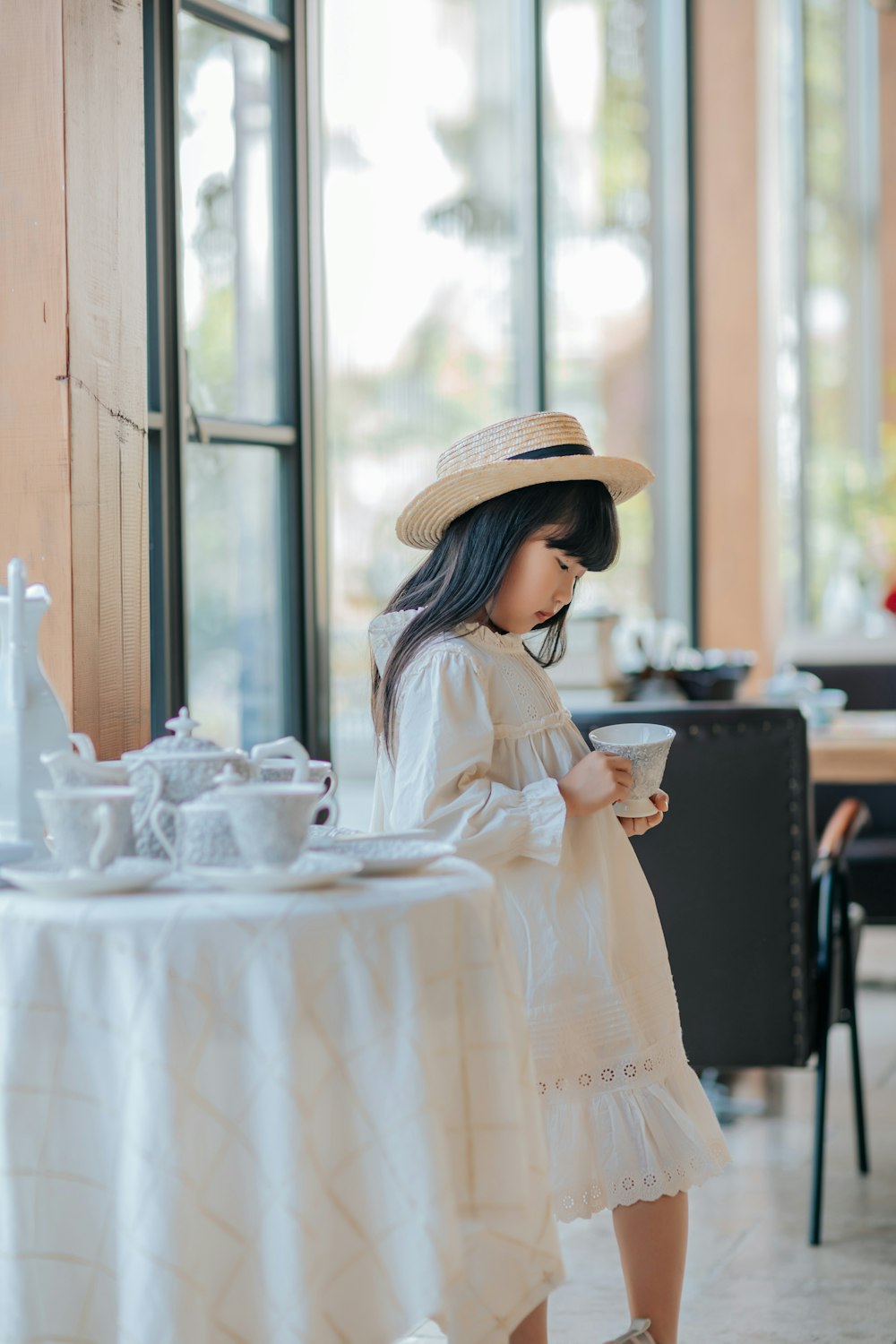 a little girl wearing a white dress and a straw hat