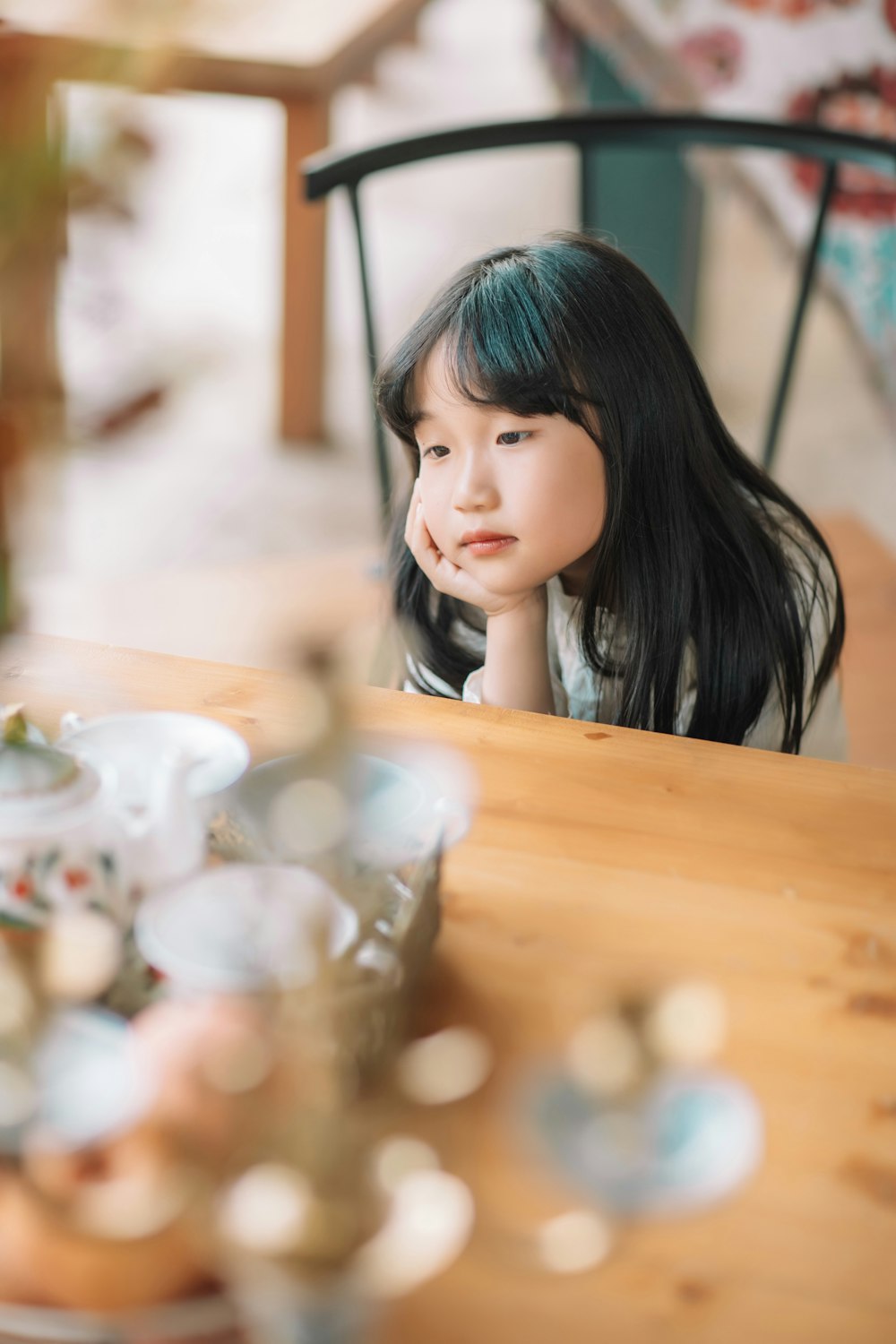 a little girl sitting at a table with a plate of food