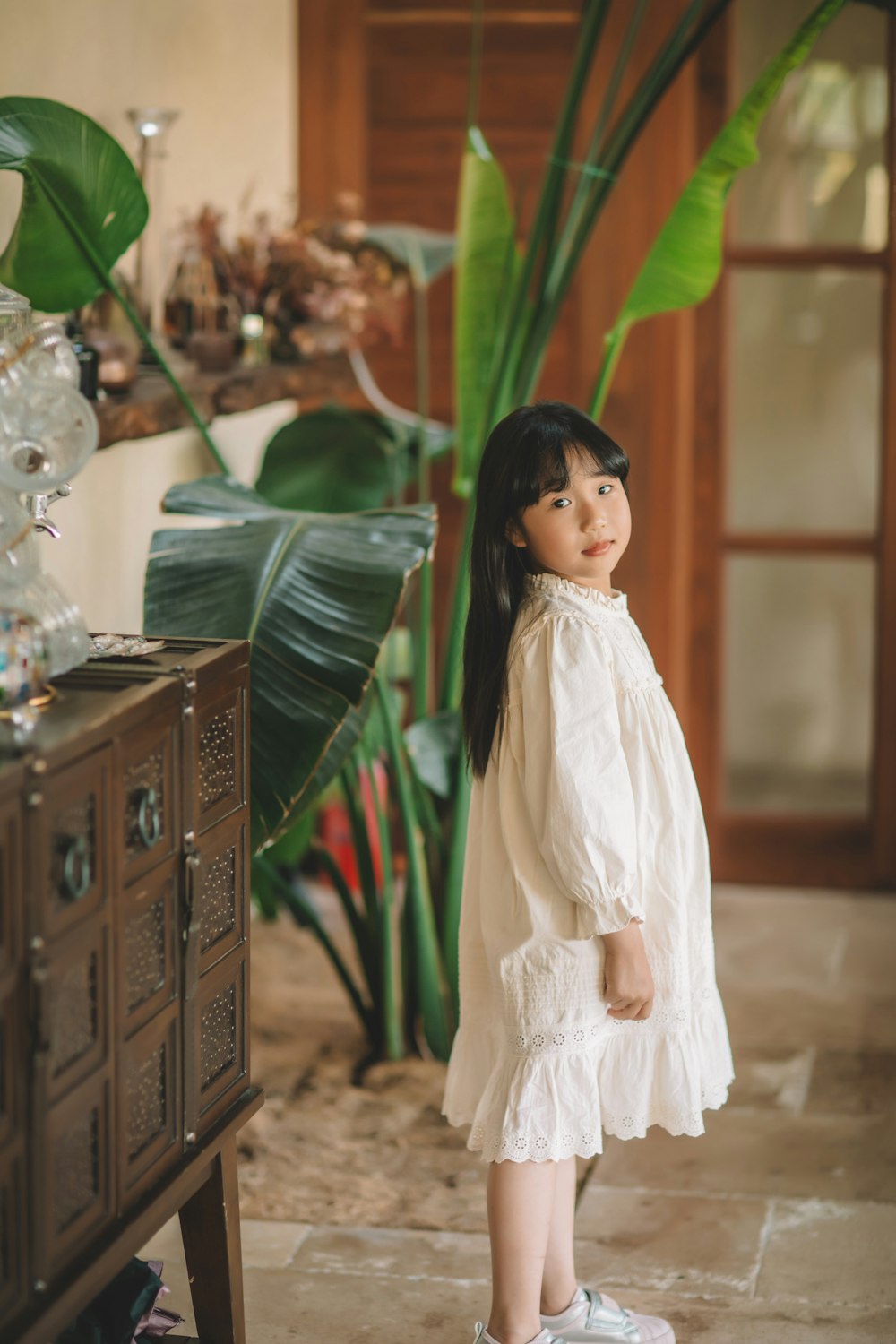 a little girl standing in front of a table