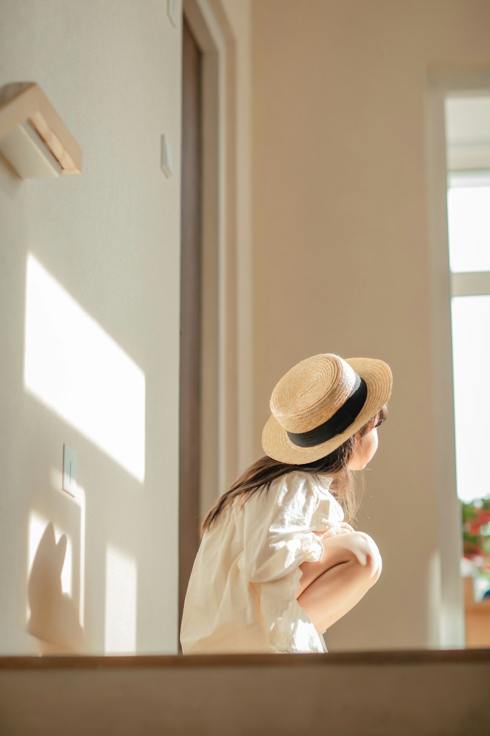 a little girl wearing a hat looking out a window