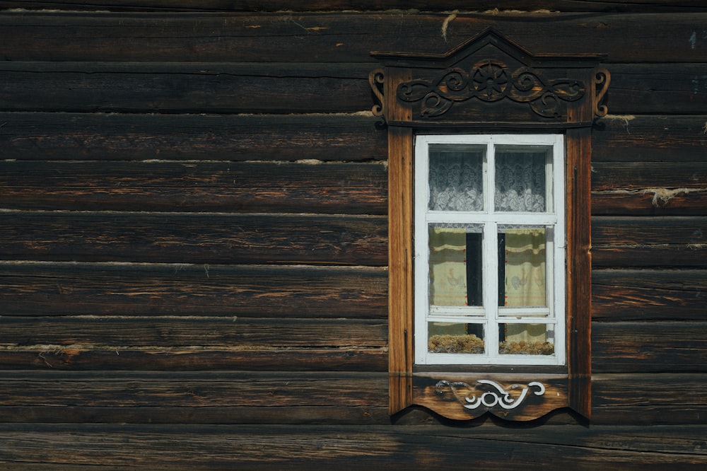 a window on a wooden wall with a curtain