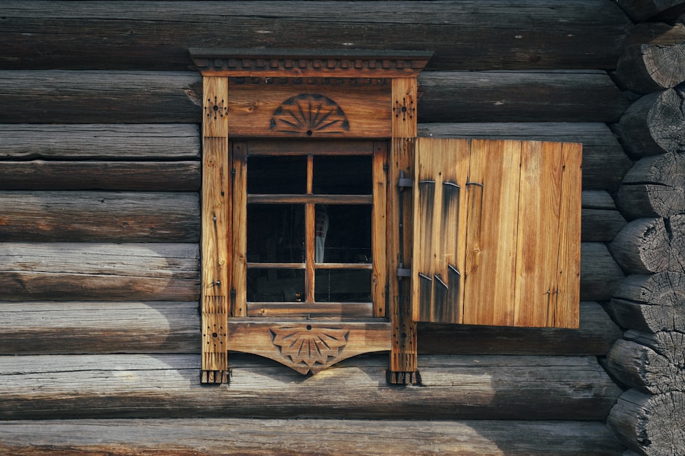 a window in a log cabin with wooden shutters