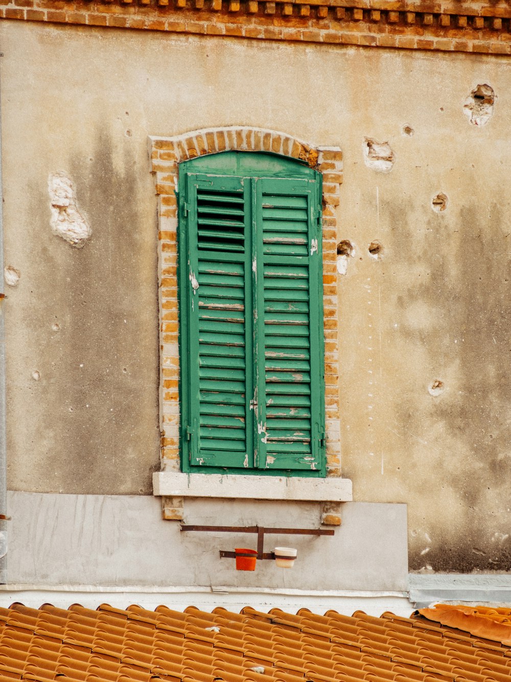 a green shuttered window on the side of a building