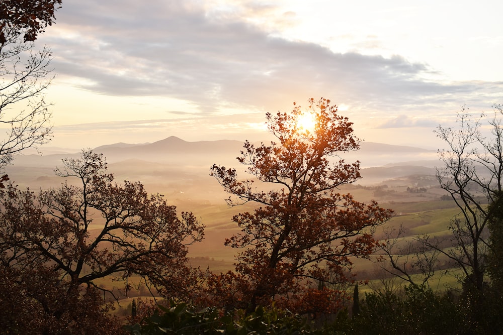 the sun shines through the clouds over a valley