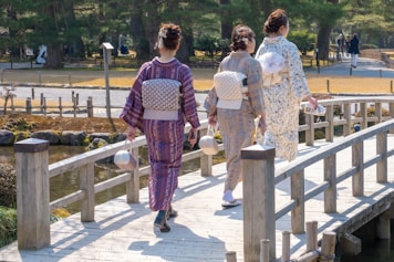 a group of women walking across a wooden bridge