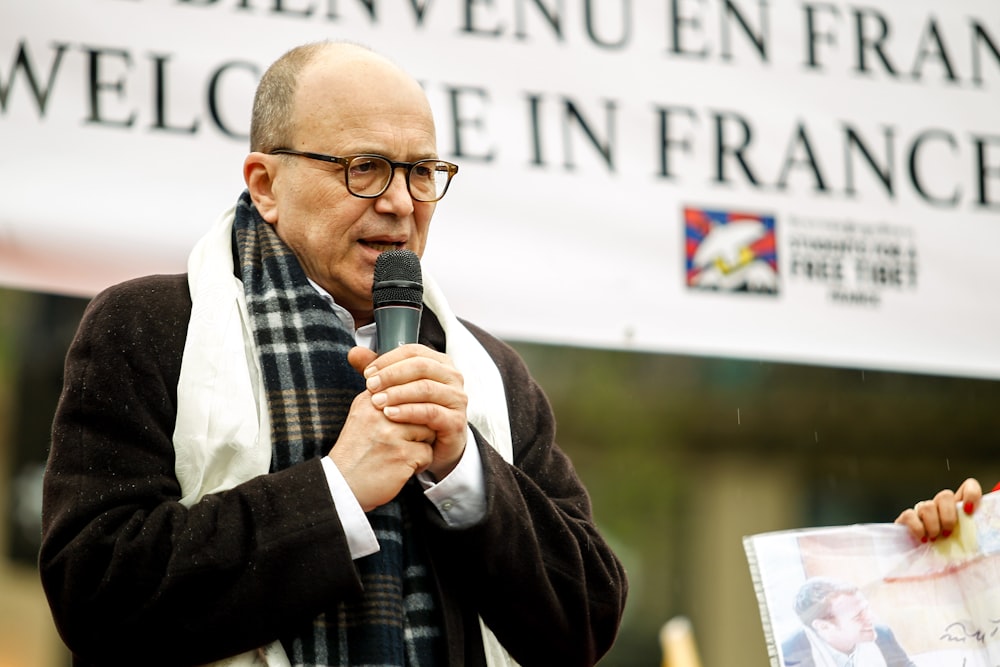 a man speaking into a microphone in front of a sign