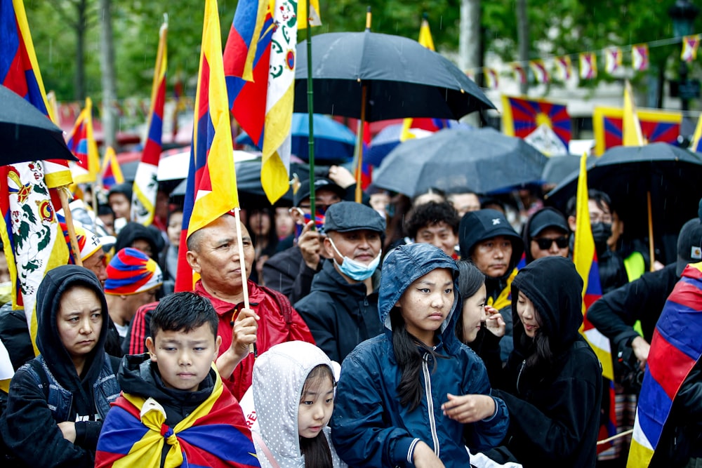 a large group of people holding flags and umbrellas