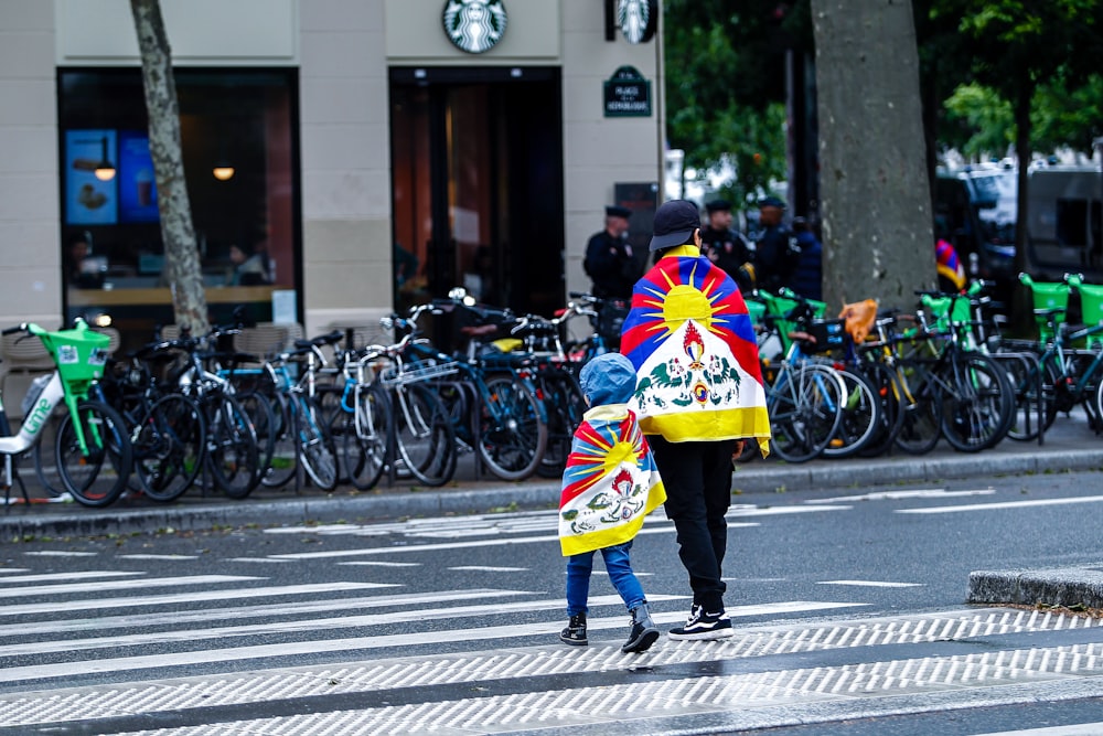 a person walking across a street holding a colorful umbrella